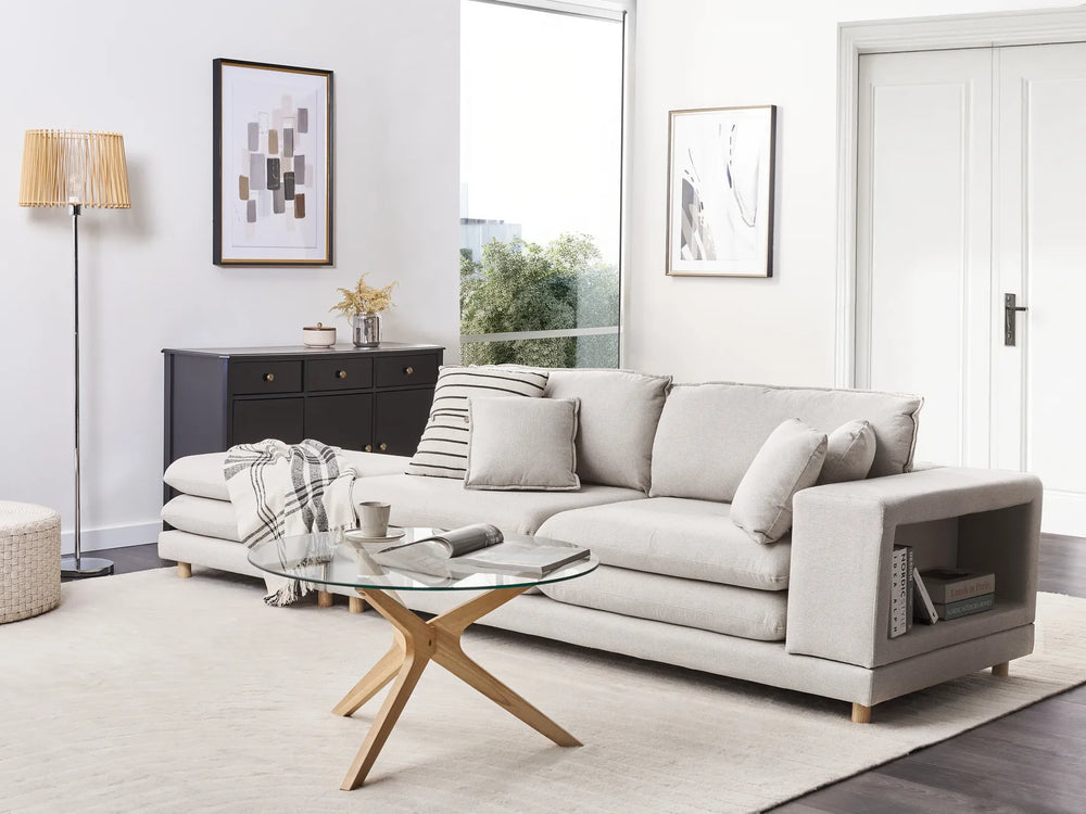 Modern living room with a gray sectional sofa, glass coffee table, and decorative items.