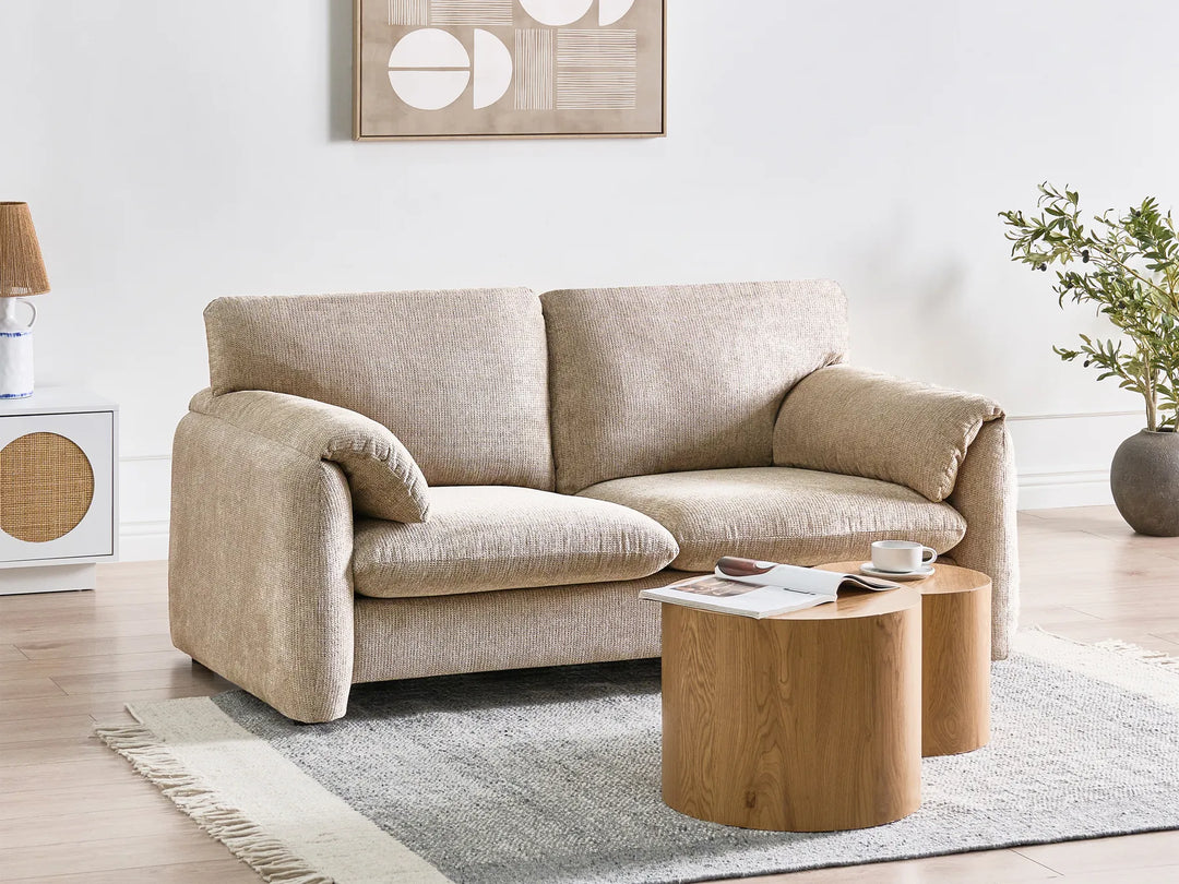 Beige sofa in a living room with a wooden coffee table and decorative items.