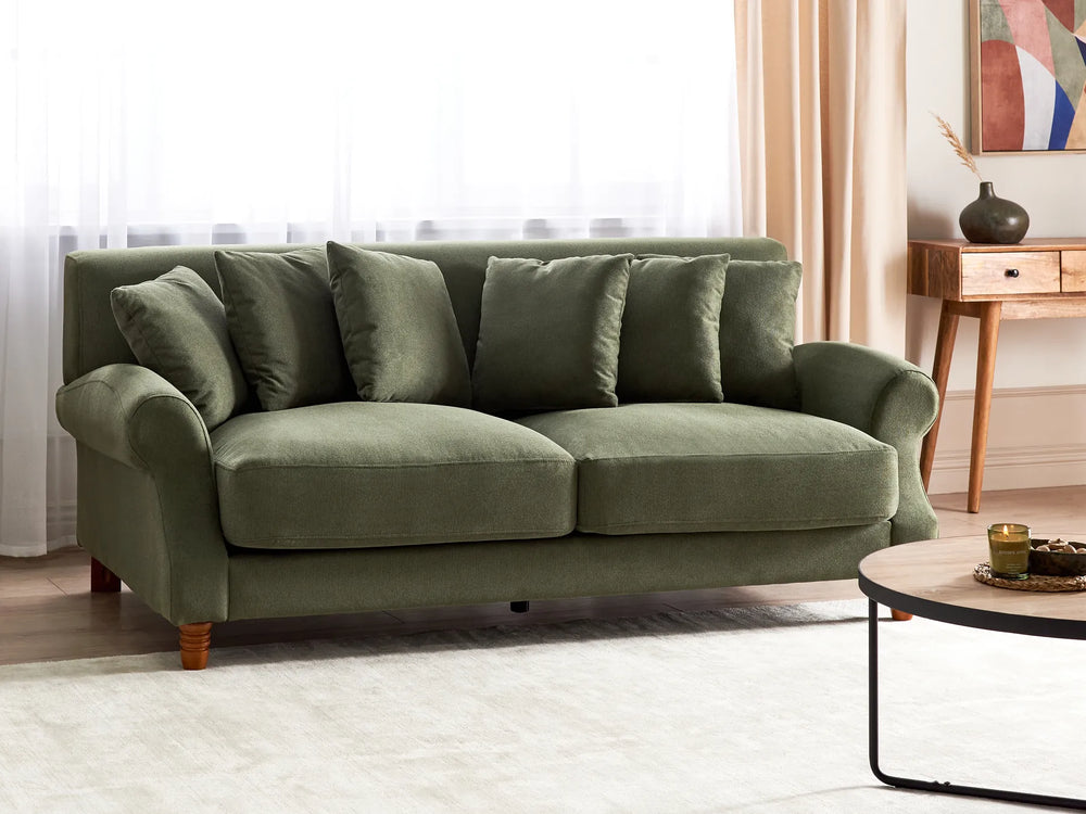Green sofa in a living room with a side table and decorative items.