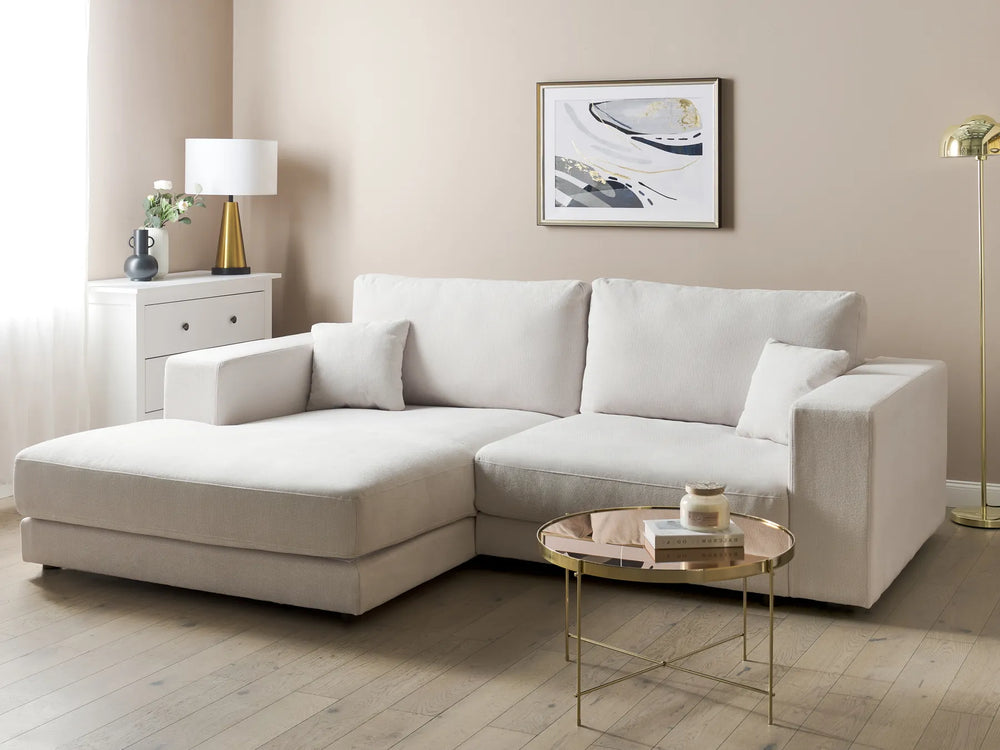 Beige sectional sofa in a living room with a coffee table and decorative items.