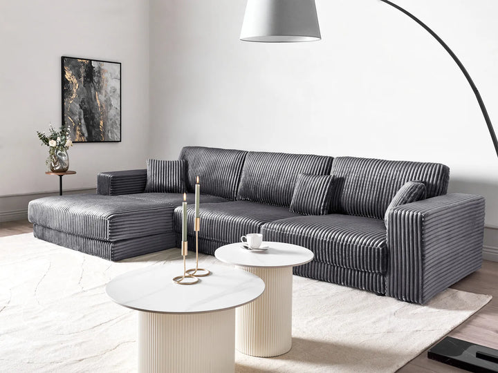 Modern living room with a gray sectional sofa, white coffee table, and decorative elements.