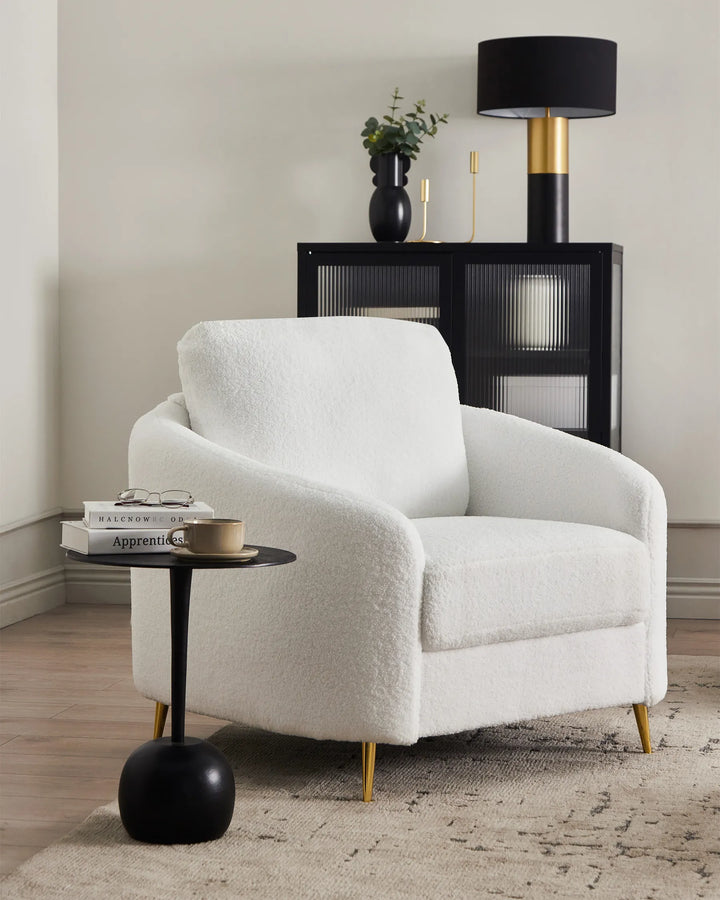 White armchair in a room with a side table and lamp