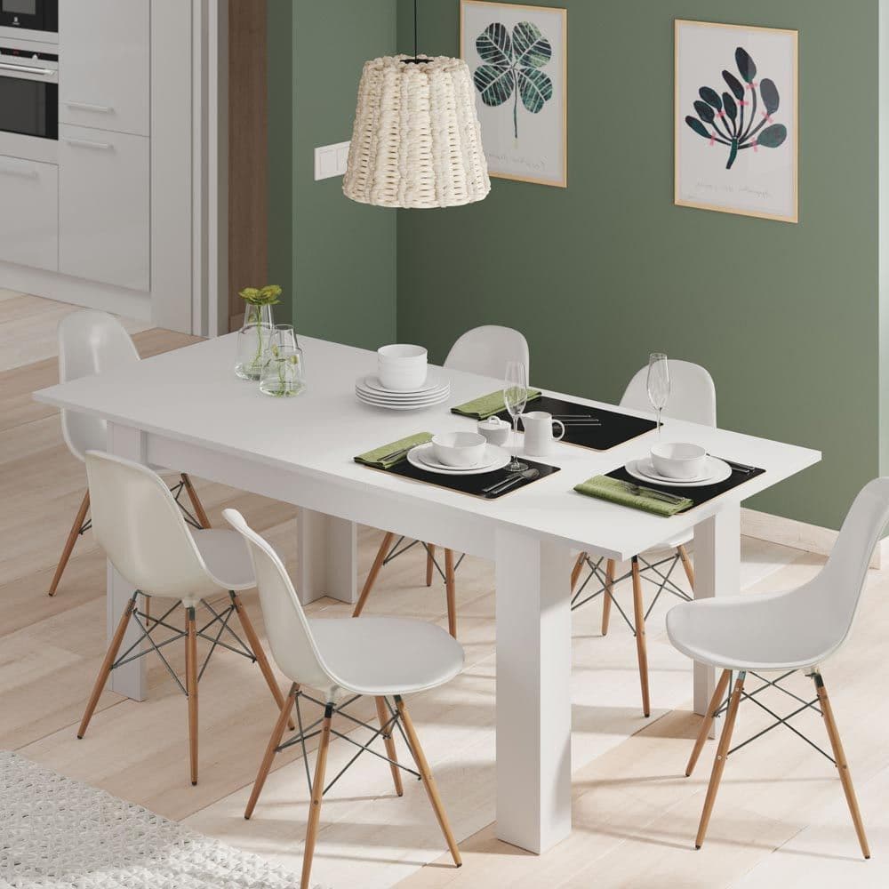 Dining room with a white table and chairs against a green wall.