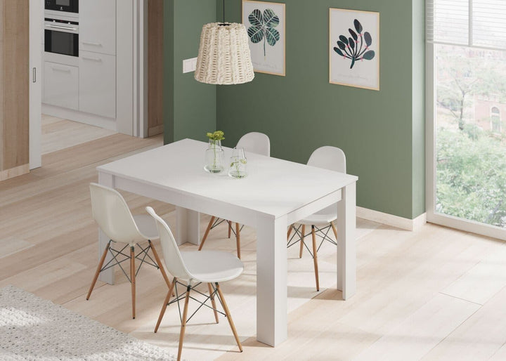 Modern dining area with a white table and chairs in a room with green walls and large windows.
