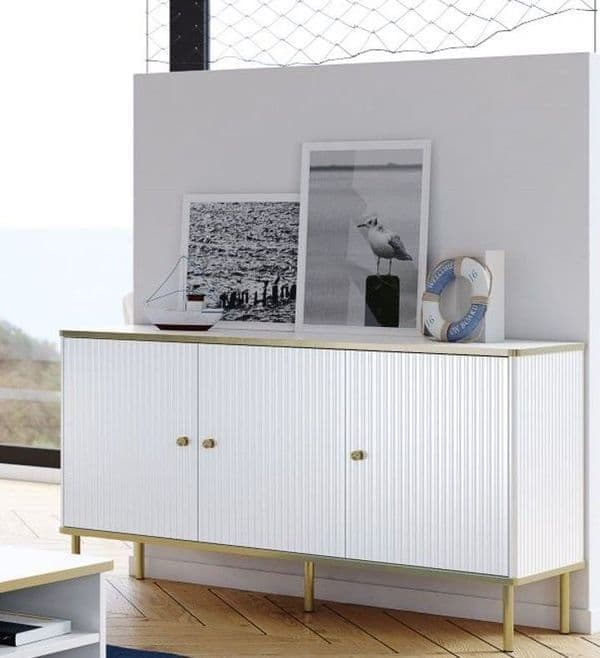 White sideboard with gold legs against a light gray wall with framed pictures.