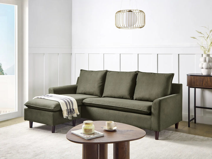 Green sectional sofa in a living room with a wooden coffee table and decorative items.