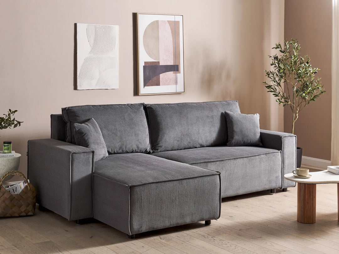 Gray sectional sofa in a living room with abstract art and a coffee table.