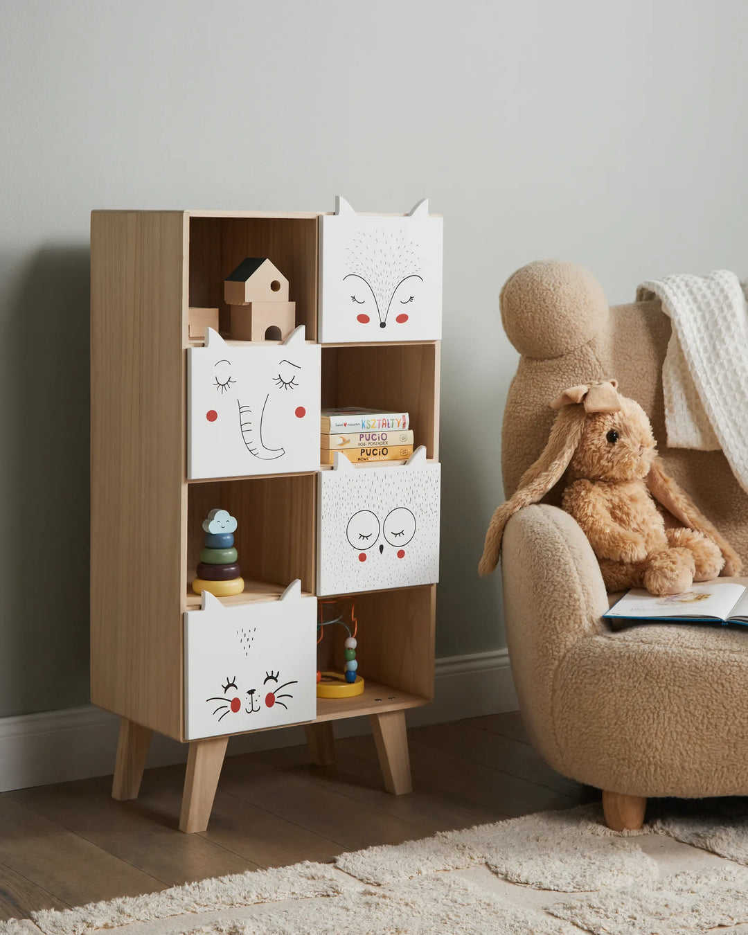 Children's room with wooden bookshelf and armchair featuring toys and books.