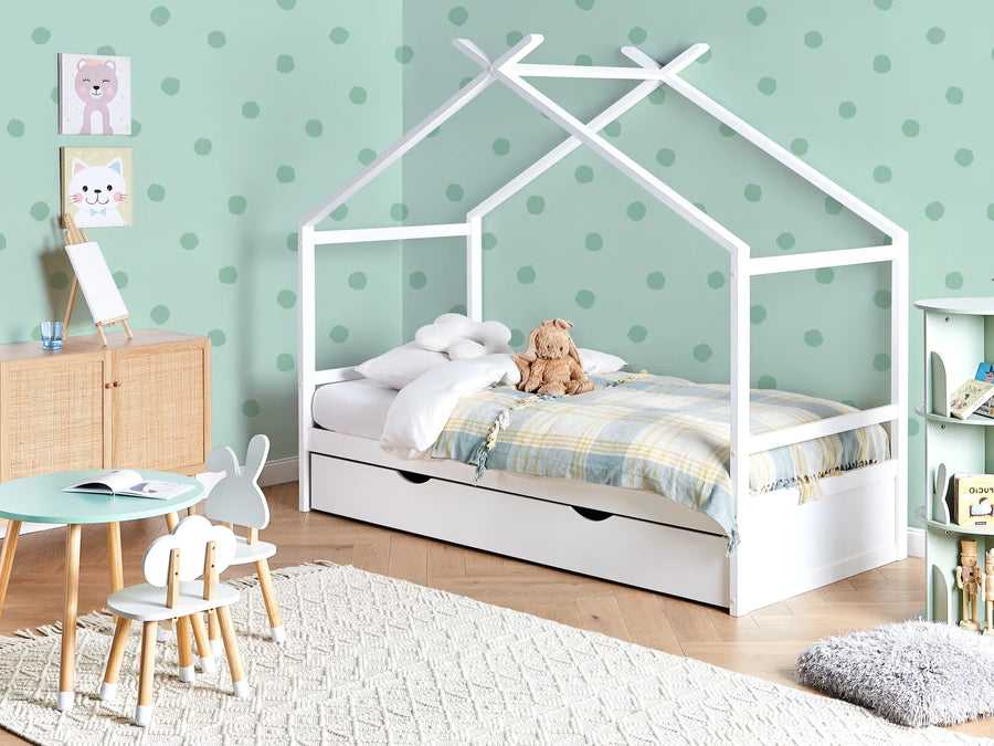 Children's room with a white house-shaped bed, teddy bear, and polka dot wallpaper.