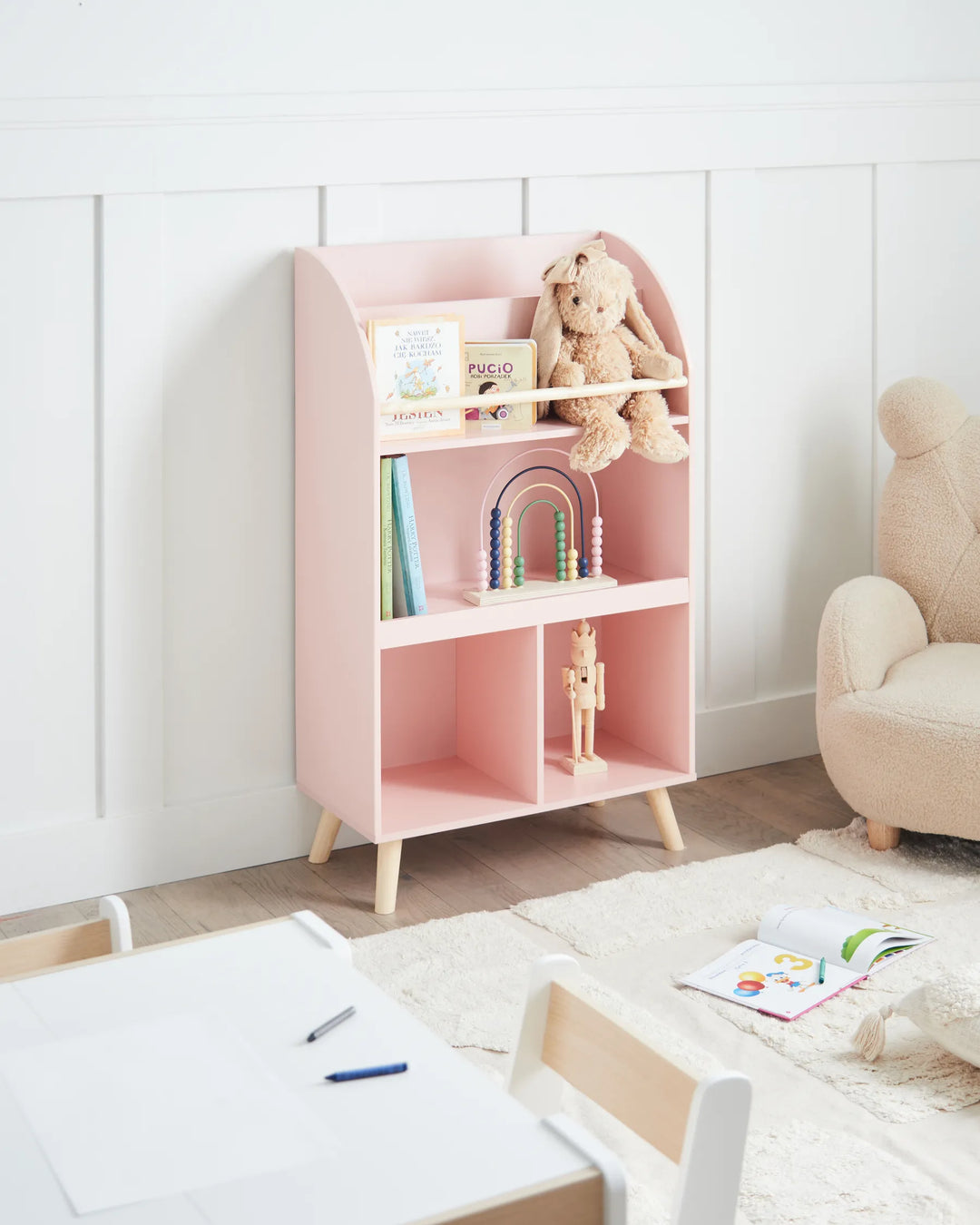 Pink children's bookshelf with toys in a room setting