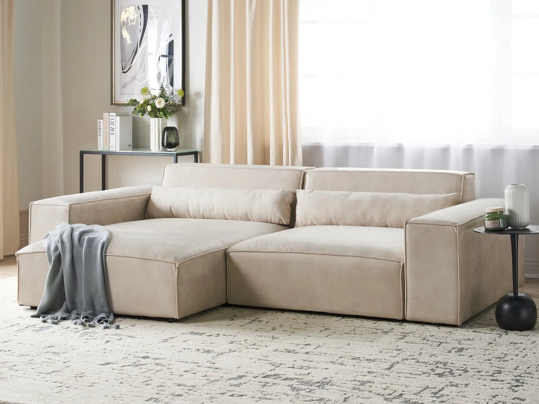 Beige sectional sofa in a living room setting with decor elements.