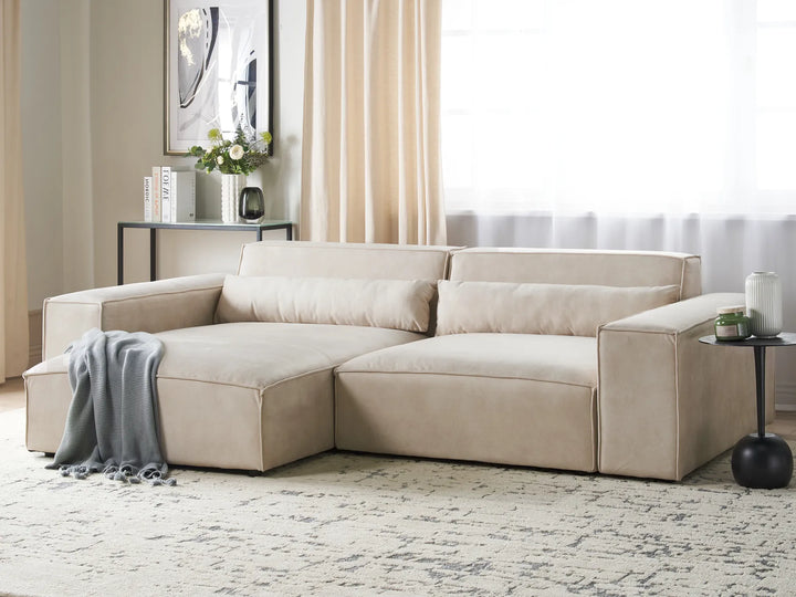 Beige sectional sofa in a living room setting with decor elements.
