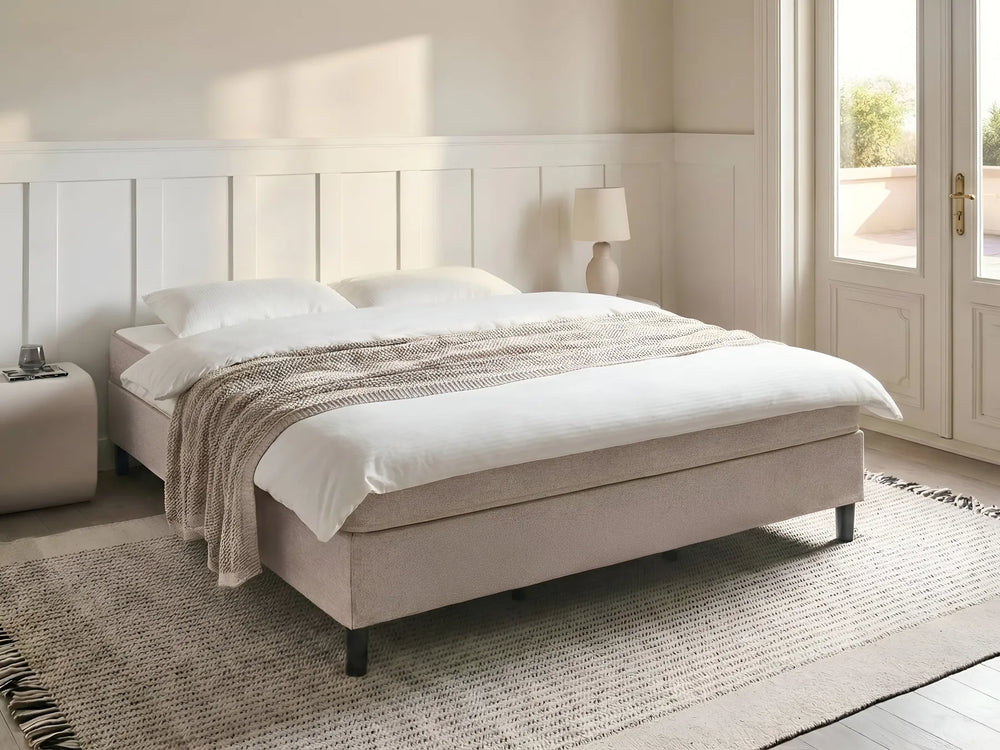 Beige bed with white bedding in a bright bedroom