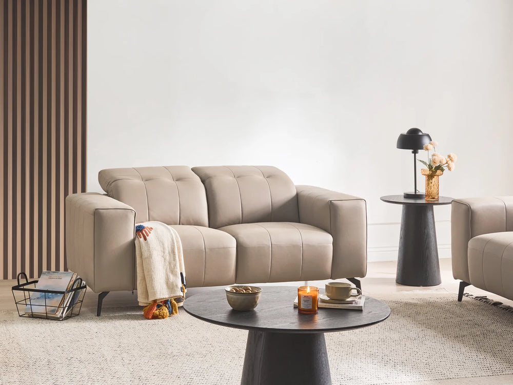 Beige sofa in a modern living room with a coffee table and decorative items.