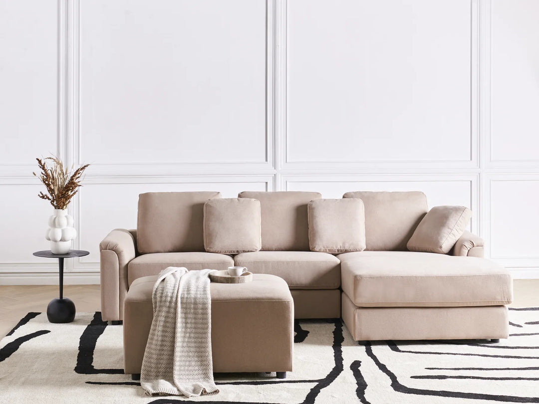 Beige sectional sofa in a living room with a white wall and decorative elements.