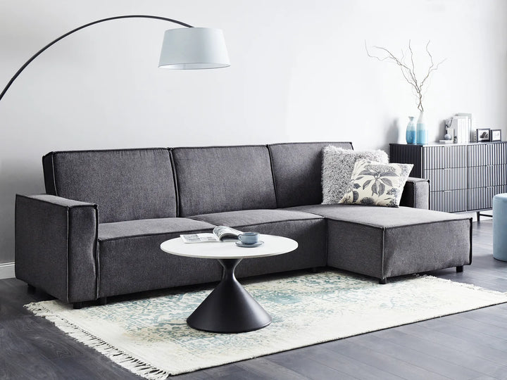 Gray sectional sofa in a living room with a round coffee table and decorative items.