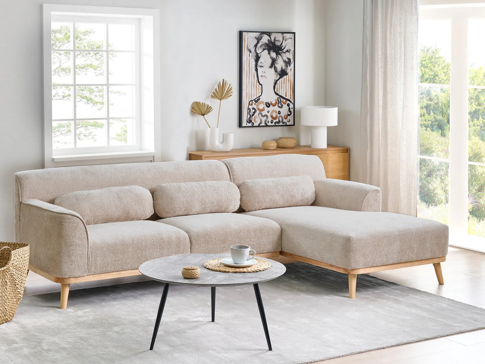 Beige sectional sofa in a living room with a coffee table and decorative items.