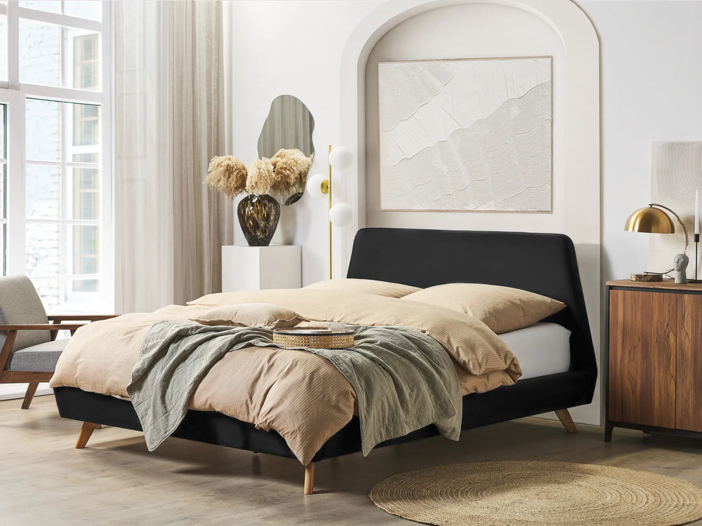 Modern bedroom with a black upholstered bed, beige bedding, and wooden furniture.
