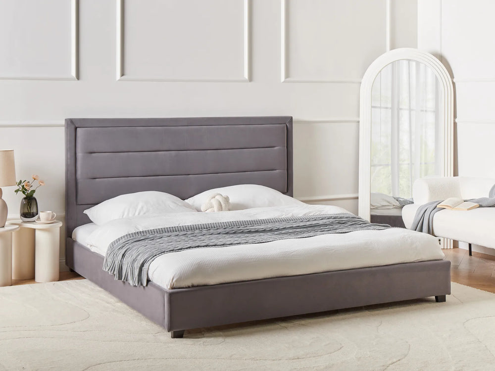 Gray upholstered bed in a bedroom setting with a mirror and nightstands.