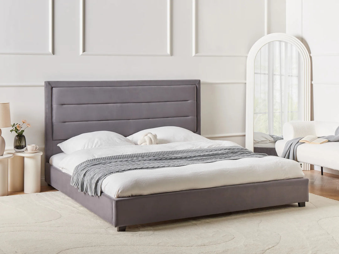 Gray upholstered bed in a bedroom setting with a mirror and nightstands.