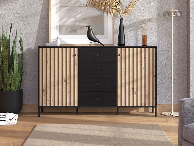Wooden sideboard with black drawers in a room with a plant and mirror.