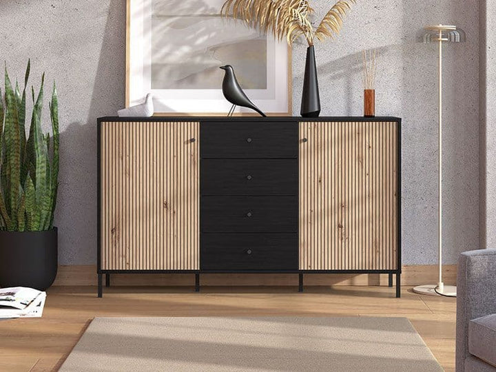 Wooden sideboard with black drawers in a room with a plant and mirror.