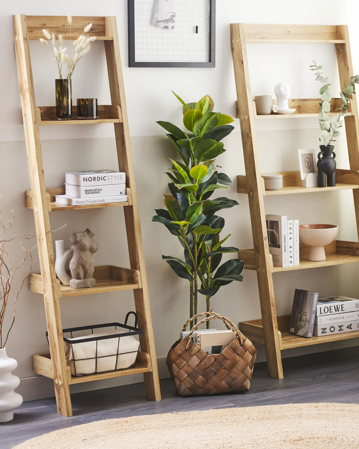 Two wooden ladder shelves with decorative items in a room setting.