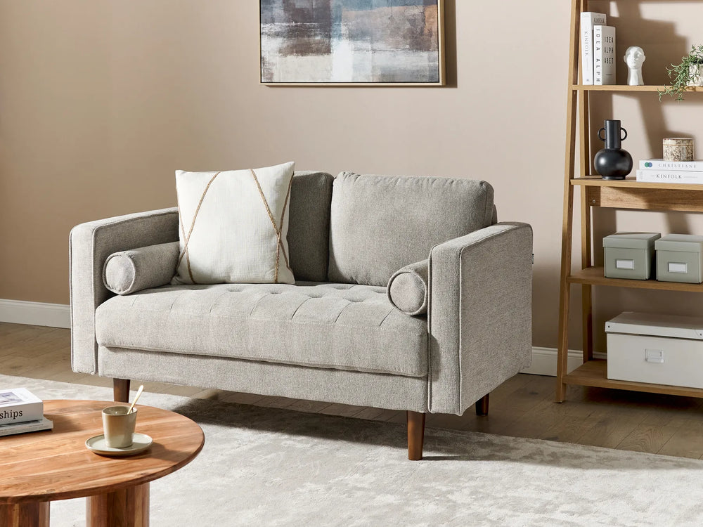 Gray sofa in a living room with a wooden side table and bookshelf.