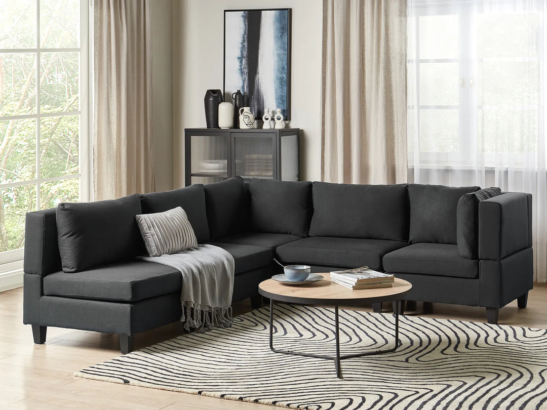 Modern living room with a black sectional sofa, coffee table, and decorative items.