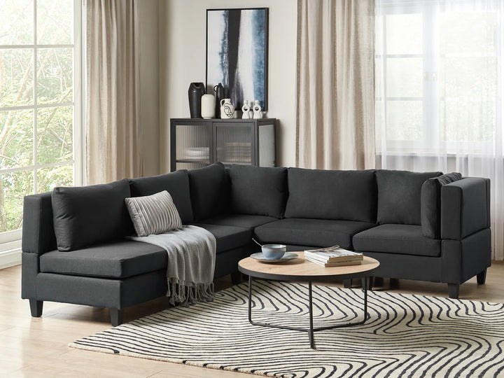 Modern living room with a black sectional sofa, coffee table, and decorative items.