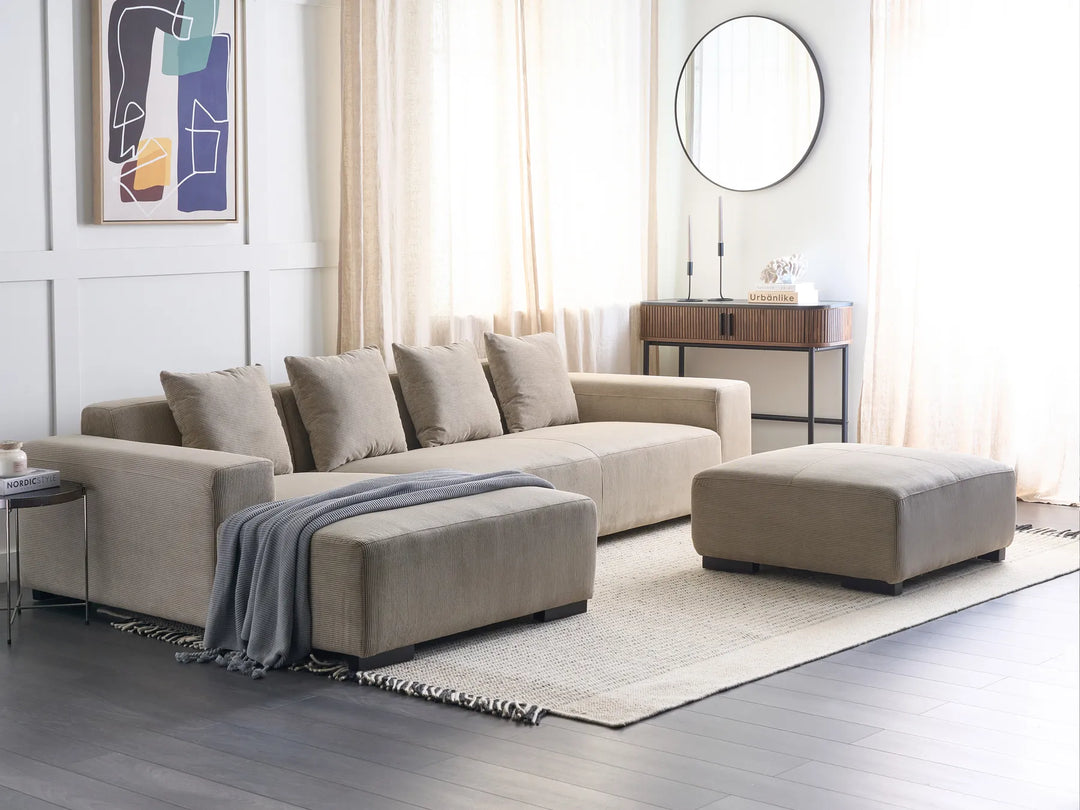 Beige sectional sofa with ottoman in a modern living room setting.