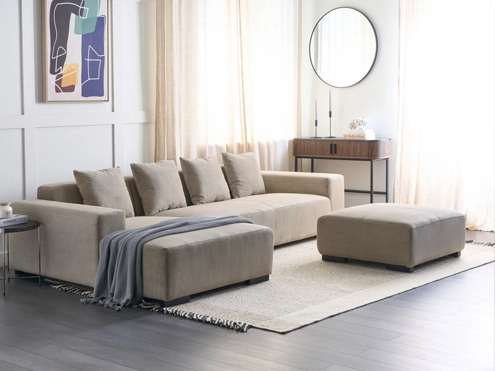 Beige sectional sofa with ottoman in a modern living room setting.
