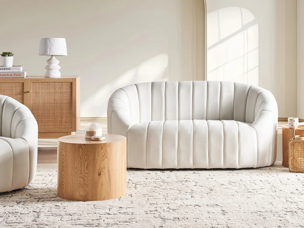 Modern living room with a white sofa, wooden side table, and light-colored walls.