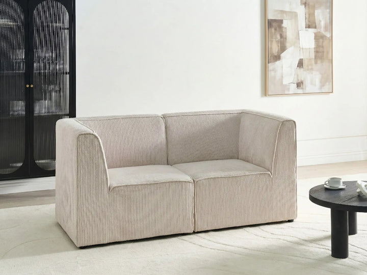 Beige sofa in a modern living room setting with a coffee table and artwork on the wall.