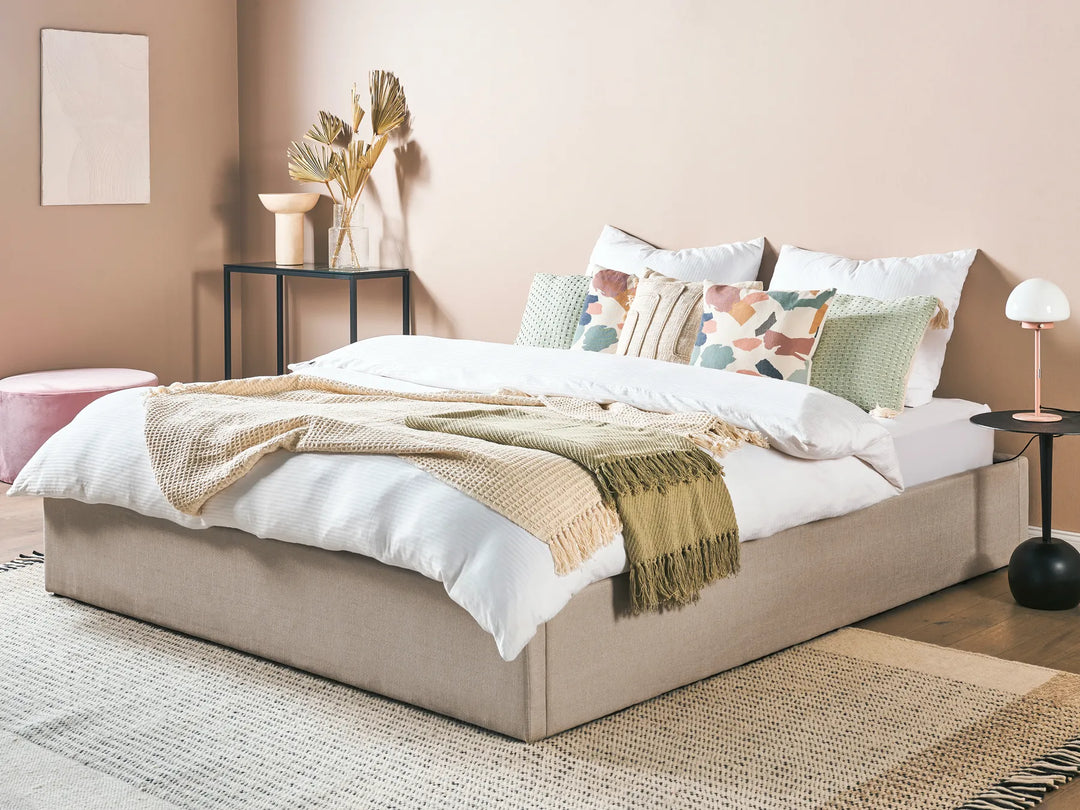 Neatly made bed with decorative pillows and a blanket in a bedroom setting.