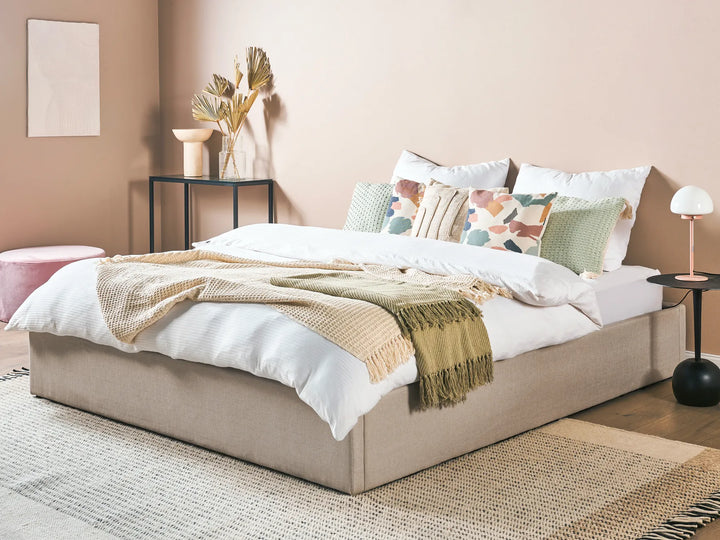 Neatly made bed with decorative pillows and a blanket in a bedroom setting.