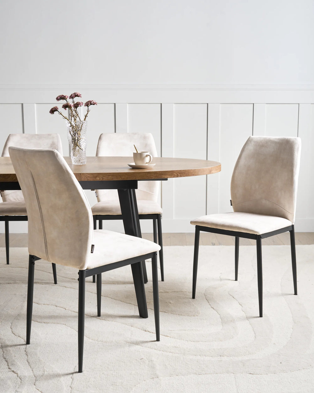 Light beige fabric dining chairs with tall backrests and black metal legs arranged around a dining table in a bright, modern dining space with minimalist décor.