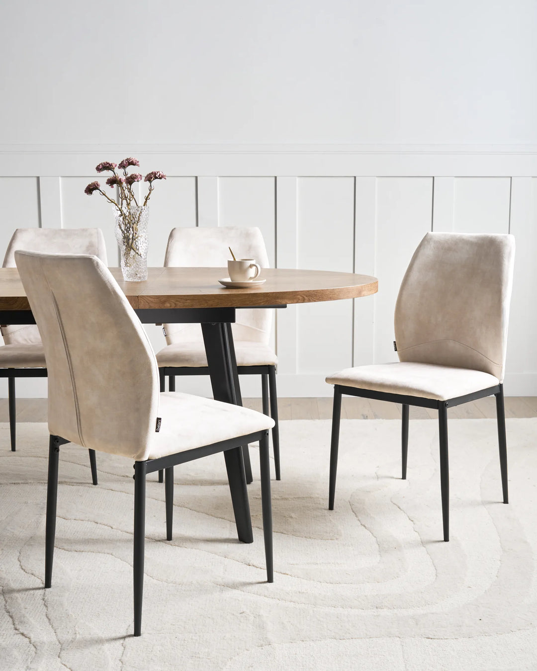 Light beige fabric dining chairs with tall backrests and black metal legs arranged around a dining table in a bright, modern dining space with minimalist décor.