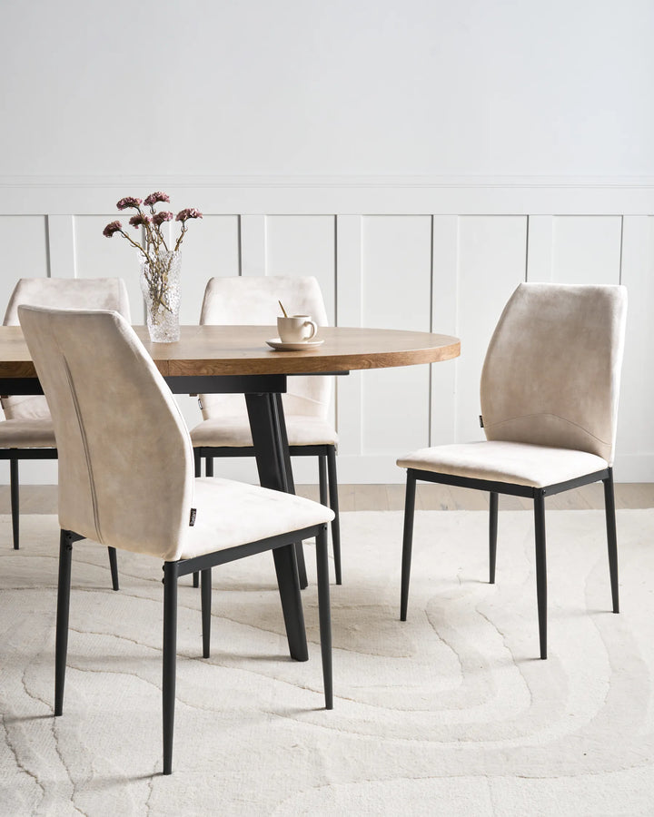 Light beige fabric dining chairs with tall backrests and black metal legs arranged around a dining table in a bright, modern dining space with minimalist décor.