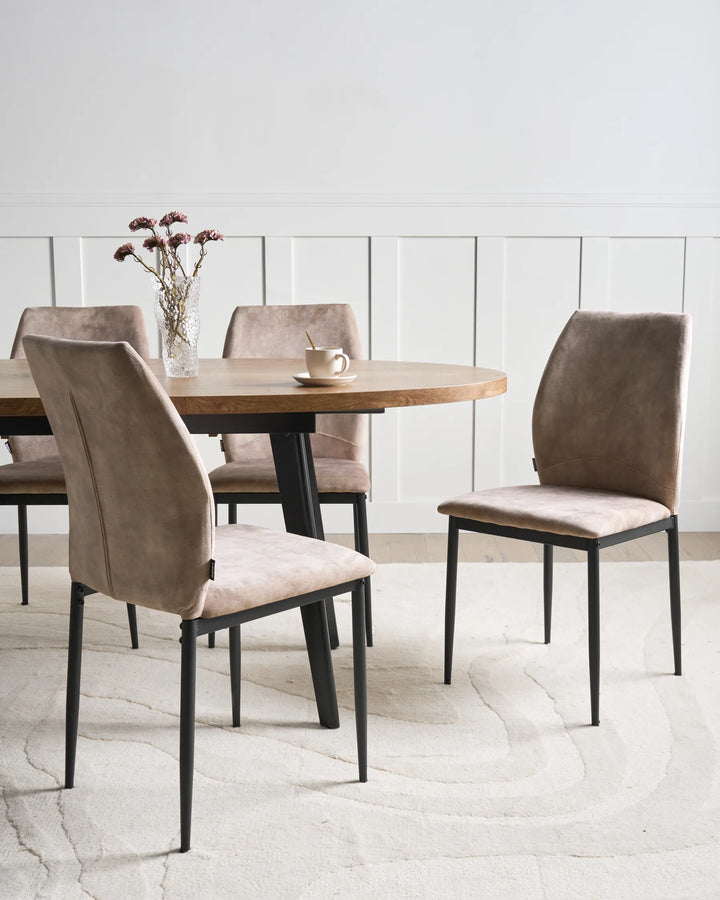 Taupe fabric dining chairs with tall backrests and black metal legs arranged around a dining table in a bright, modern dining space with minimalist décor.