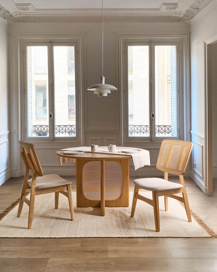 Styled within an elegant, light-filled dining space, this cane-back dining chair brings warmth and natural texture to the room. The combination of oak-toned wood, woven rattan detailing, and a neutral upholstered seat creates a relaxed yet refined aesthetic. Perfect for Scandinavian, coastal, and modern organic interiors, it offers comfortable seating while enhancing the dining area with timeless character and understated sophistication.