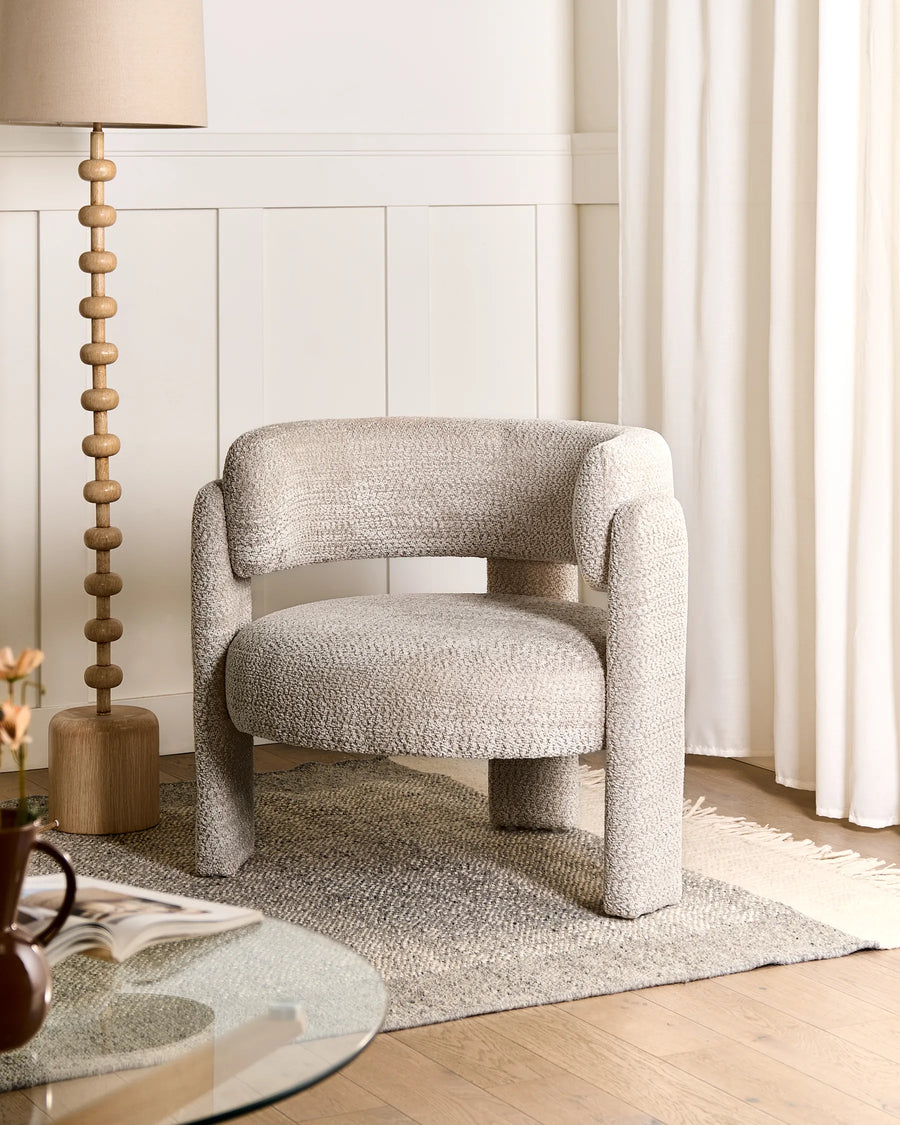 Beige textured armchair in a room with a lamp and curtains
