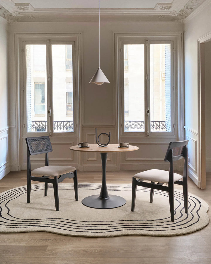 Black cane-back dining chairs styled in an elegant, light-filled dining space with minimalist décor, soft neutral tones, and refined architectural details, creating a modern Parisian and contemporary luxury atmosphere.