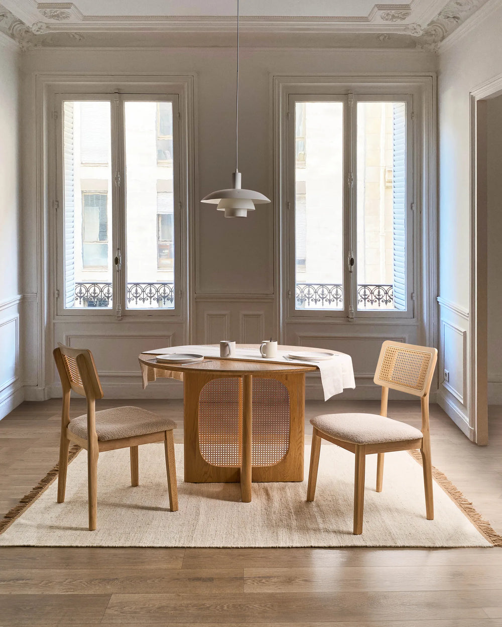 Displayed in a sophisticated dining setting, this cane-back dining chair brings effortless charm and natural character to the space. The warm wood tones, woven rattan detailing, and soft boucle seat complement the airy room, creating a light and inviting atmosphere. Ideal for casual dining, modern farmhouse interiors, or relaxed entertaining spaces, it blends timeless craftsmanship with contemporary comfort.