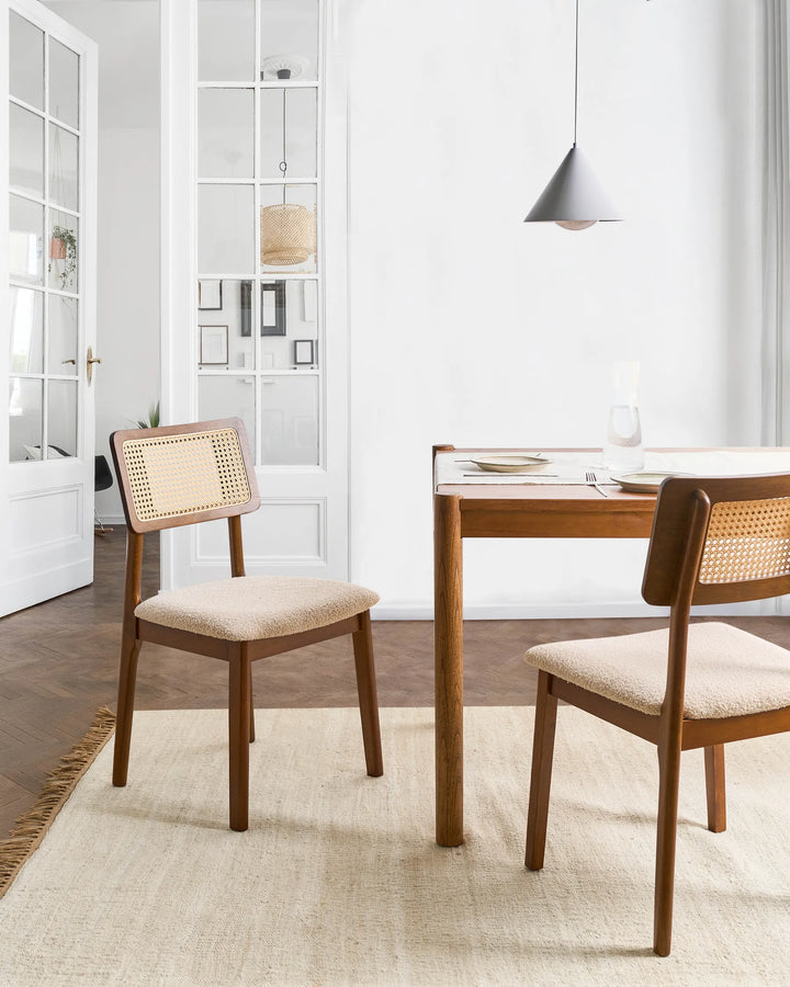 Placed within a bright and elegant dining space, this cane-back dining chair adds warmth, texture, and timeless character to the room. The walnut-toned frame contrasts beautifully with the light boucle seat and woven rattan panel, creating a refined yet relaxed aesthetic. Perfect for everyday dining and entertaining, it brings a touch of organic craftsmanship and modern elegance to any dining setting.