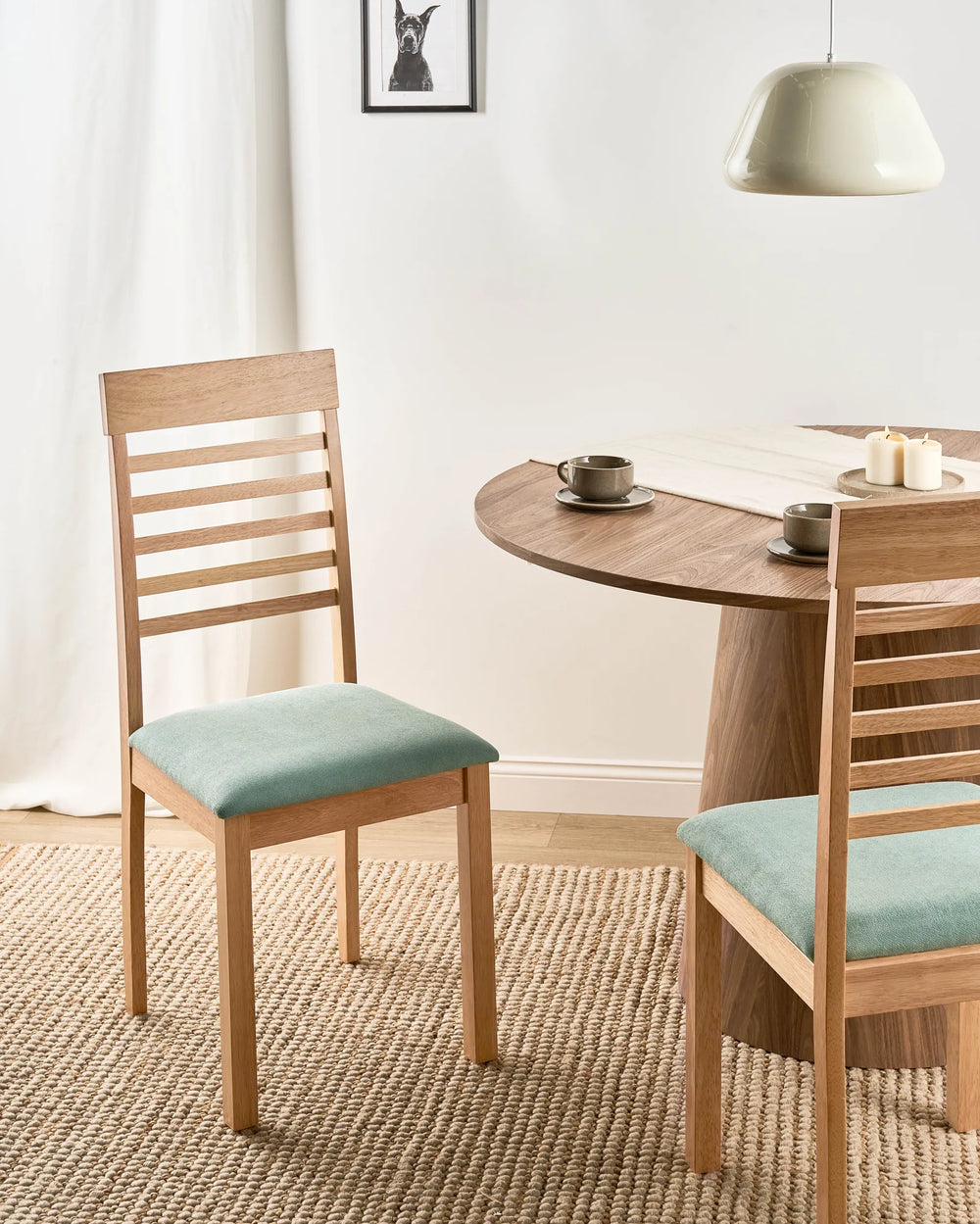 Presented in a bright, Scandinavian-inspired dining setting, this wooden dining chair brings warmth and subtle colour to the room. The light oak frame pairs beautifully with the muted green upholstered seat, creating a fresh and inviting look. Its classic slatted back and comfortable cushioning make it ideal for casual family meals, modern dining rooms, and relaxed entertaining spaces.