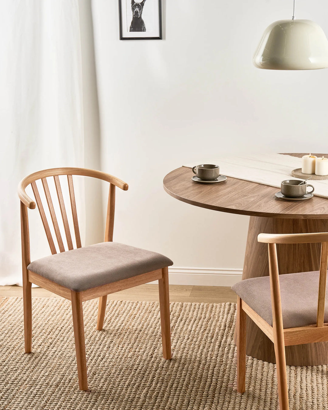 Light wood dining chairs with taupe upholstered seats around a wooden dining table in a modern dining room.