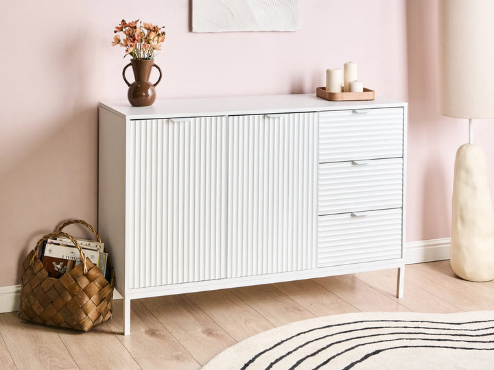 White cabinet with decorative items against a pink wall
