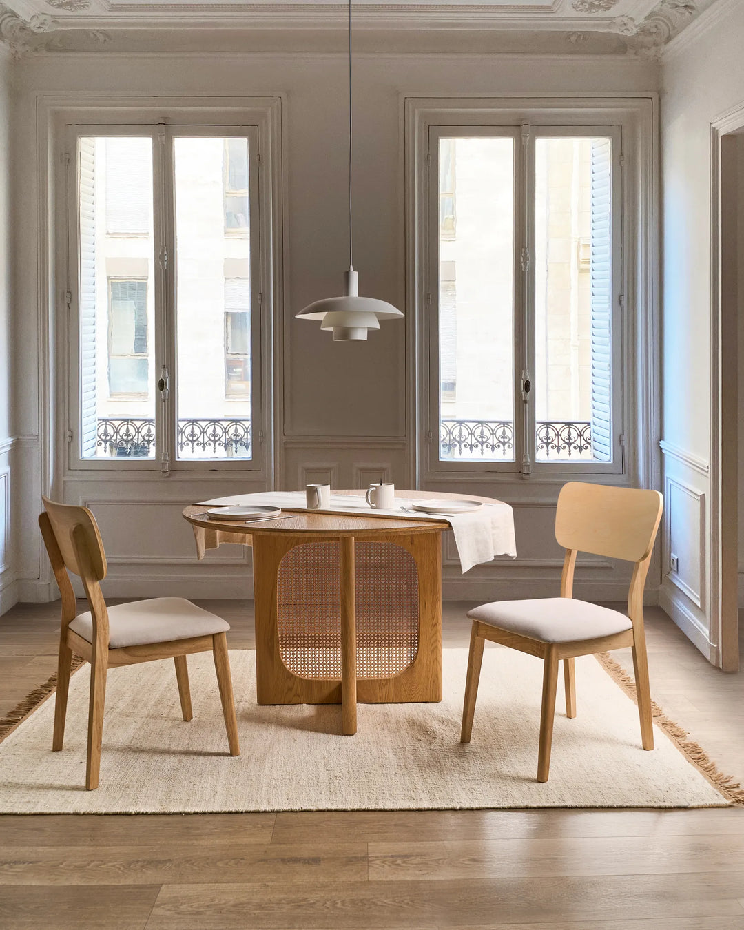 Light wood dining chairs styled around a round table in an elegant, airy dining room, creating a soft, natural, and timeless atmosphere with cozy neutral tones.