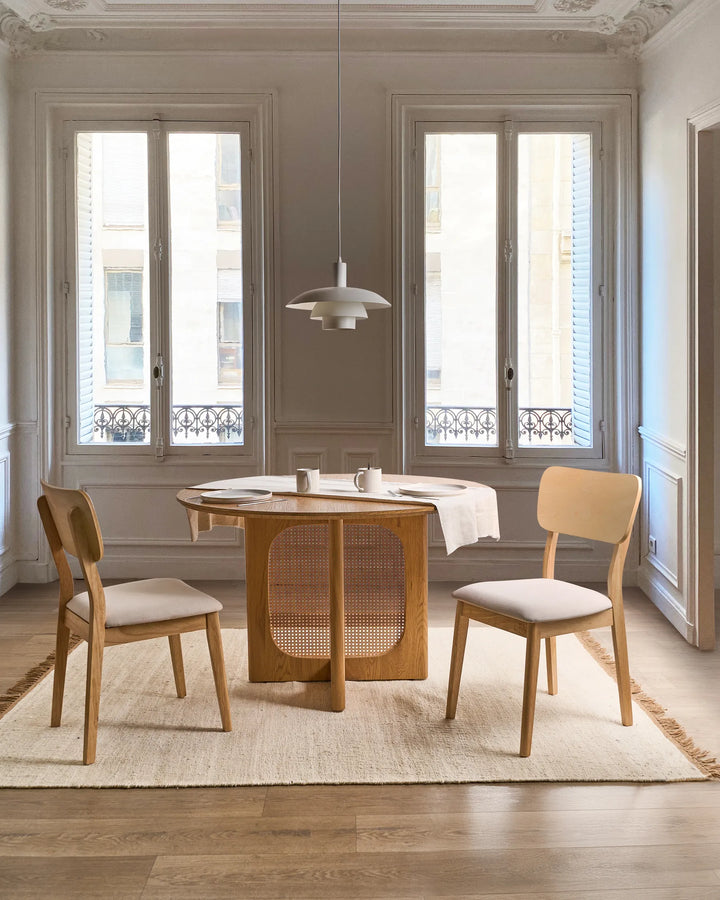 Light wood dining chairs styled around a round table in an elegant, airy dining room, creating a soft, natural, and timeless atmosphere with cozy neutral tones.